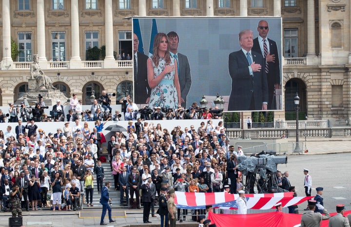 President Donald Trump and first lady Melania Trump are seen on a large screen as they stand during the U.S. national anthem during a Bastille Day parade in Paris on July 14, 2017.