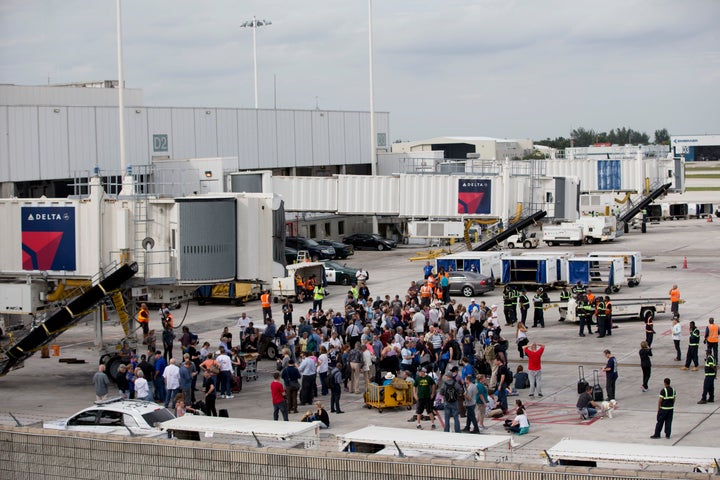 People stand on the tarmac at the Fort Lauderdale-Hollywood International Airport after a shooter opened fire inside a termin