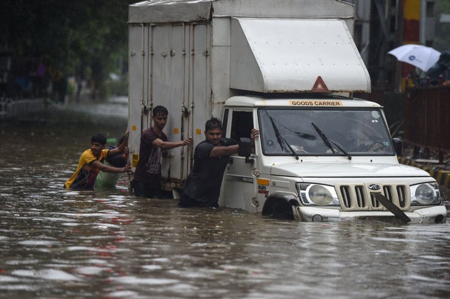 Men push truck on a flooded street after heavy rain showers in Mumbai on July 1,