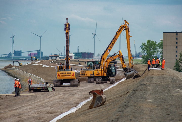 Construction workers raise a 12 kilometer stretch of a sea dike by 2 meters to meet new safety standards made necessary by sea level rise, near Delfzijl in the Netherlands.