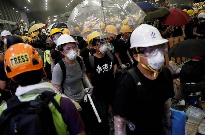 Anti-extradition bill protesters wearing helmets gather outside the Legislative Council building on the anniversary of Hong K