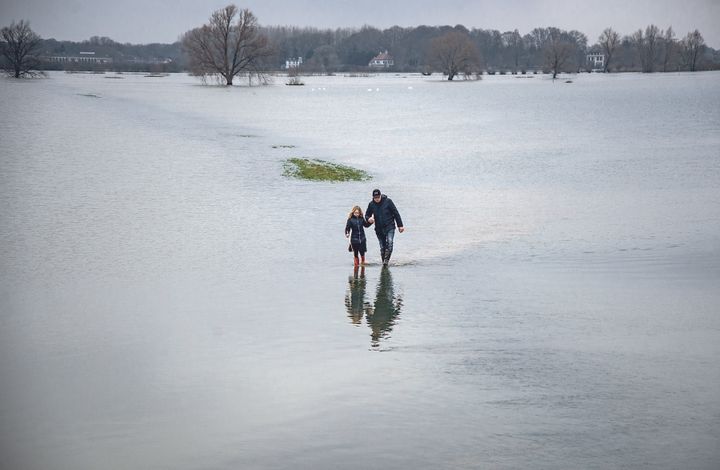 A father and his daughter wade through farmland that is flooded by the Ijssel river. High water levels have led the Dutch to move river levees back to create more space for water.