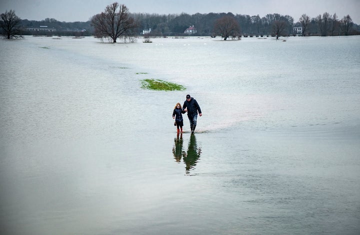 <em>A father and his daughter wade through farmland that is flooded by the Ijssel river. High water levels have led the Dutch