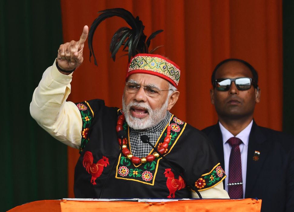 Prime Minister Narendra Modi gestures while addressing a Bharatiya Janata Party rally, dressed in traditional Khasi tribe attire and Garo tribe headgear, in Shillong on December 16, 2017. 