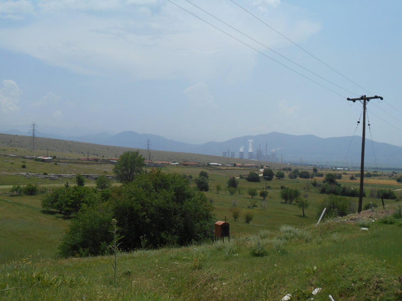 Στα όρια του χωριού της Ακρινής, κτηνοτροφικές μονάδες και εκτάσεις, με φόντο τον ΑΗΣ Αγ. Δημητρίου.