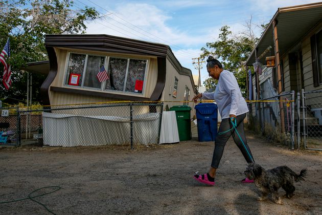 Carmen Rivera, 65, on morning walk with her dog Ash passes by a mobile home dislodged in Torusdale Estates mobile home park by the earlier 6.4 earthquake in Ridgecrest. 