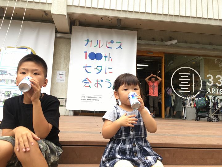 「カルピス100th 七夕に会おう展」が行われている3331 Arts Chiyodaの入口で、「カルピスウォーター」を飲む子どもたち（無料で配布されていた）