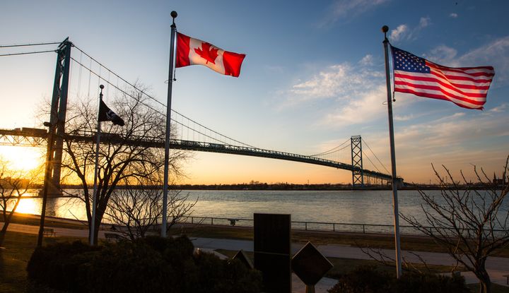 The Ambassador Bridge, linking Detroit, Mich., Windsor, Ont., with Canadian and U.S. flags in the foreground.