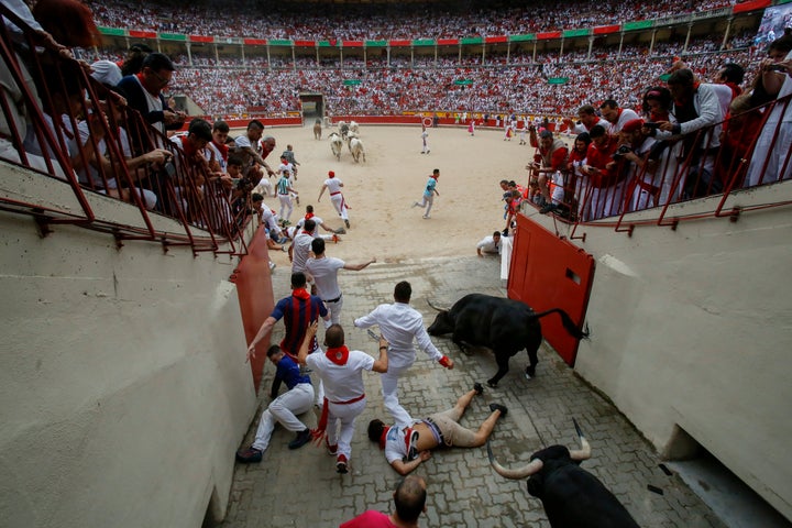 An unidentified runner appears to lie unconscious near the bullring as other runners and bulls trample him.