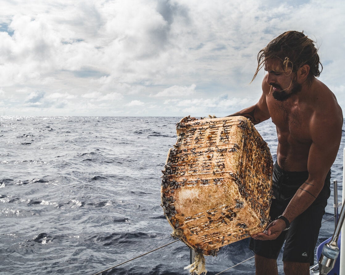 A member of the Vortex Swim team holds a laundry hamper or storage basket covered in aquatic life.