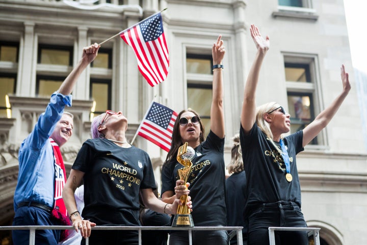 Alex Morgan, center, holds the World Cup trophy with teammate Megan Rapinoe at the parade.