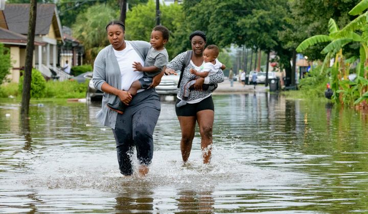 Jalana Furlough carries her son Drew Furlough as Terrian Jones carries Chance Furlough in New Orleans after flooding Wednesday, July 10, 2019. (AP Photo/Matthew Hinton)