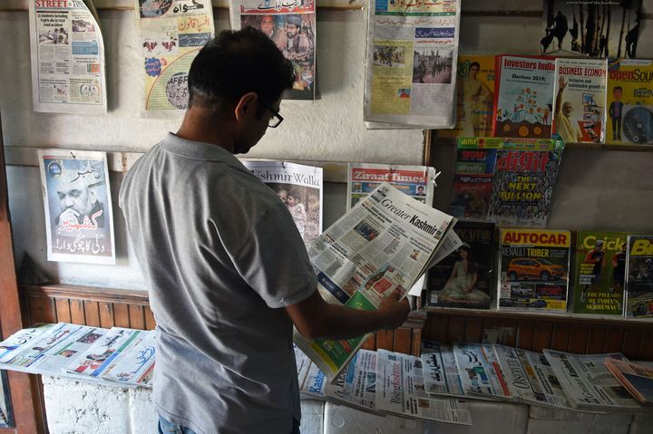 A Kashmiri man reads a newspaper at a stall in Srinagar.