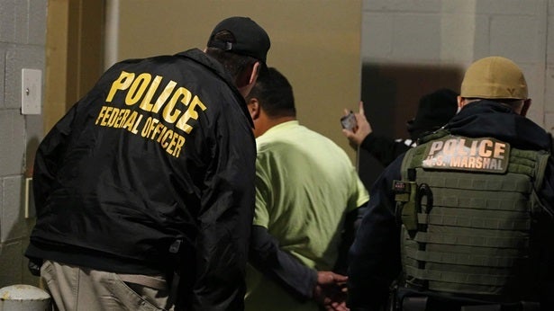 U.S. Immigration and Customs Enforcement agents escort a man to lockup during a raid in Richmond, Virginia, last year. The Tr