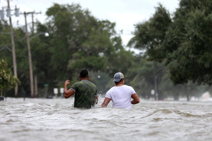 <i>People wade through a flooded street after Hurricane Barry in Mandeville, Louisiana.</i>