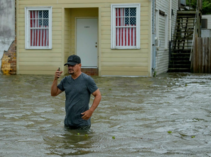 Barry Williams talks to a friend on his smartphone as he wades through storm surge from Lake Pontchartrain on Lakeshore Drive in Mandeville, La.