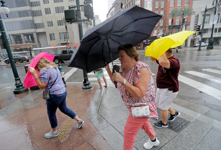 Martha Young, center, Patricia Plishka, left, and her husband Glen, right, battle the wind and rain from Hurricane Barry as i