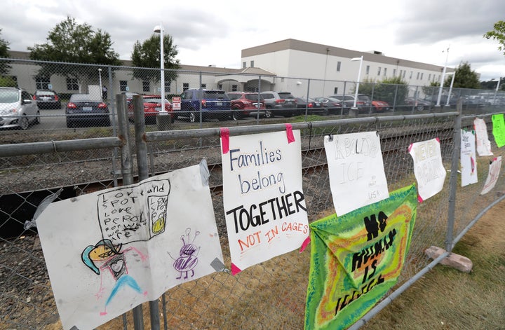 A sign that reads "Families belong Together Not in Cages" hangs on a fence outside the Northwest Detention Center in Tacoma,