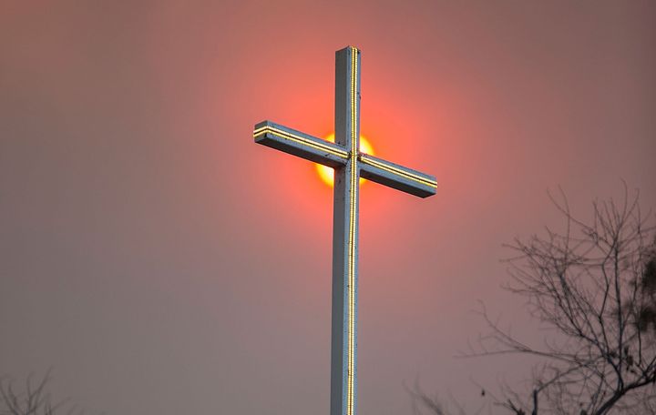 Smoke from a wildfire in California appears behind a church cross.