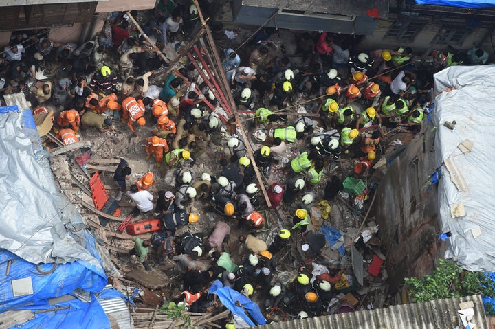 Fire brigade personnel and rescue workers look for survivors after a building collapsed in Mumbai on July 16, 2019.