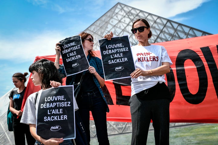 Protesters hold banners reading "Shame on Sackler" and "Take down the Sackler name" in front of the Pyramid of the Louvre Museum on July 1 in Paris.