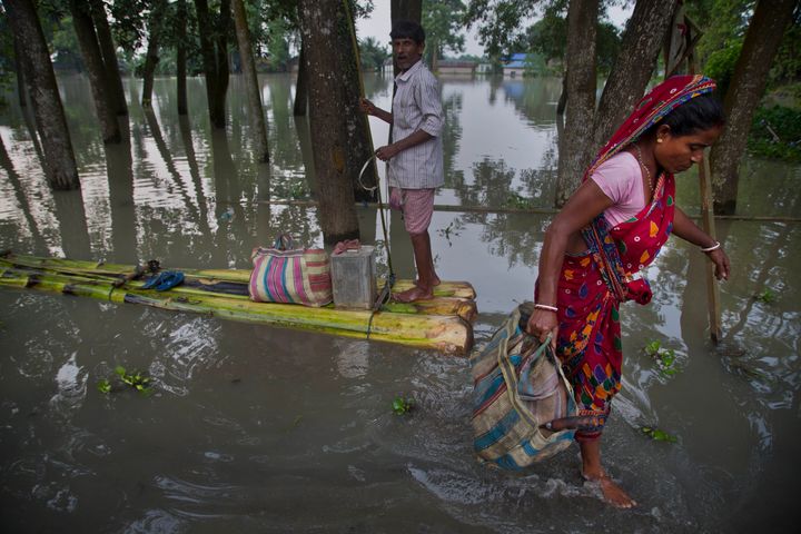 Woman gets down from a makeshift banana raft to collect relief materials in Jhargaon, east of Guwahati, Assam, on 17 July 2019.
