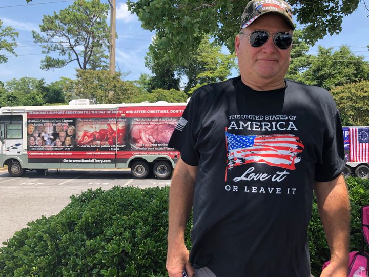 Mark Dawson, who thinks Muslims should be removed from the U.S., poses for a photo outside the Williams Arena in Greenville. Behind him is a trailer plastered with images of dead fetuses. 