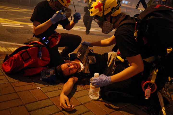 Medical workers help a protester in pain from tear gas fired by policemen on a street in Hong Kong.