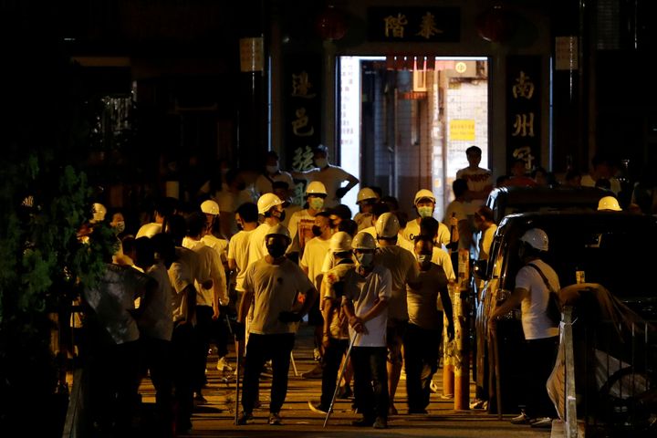 Men in white T-shirts and carrying poles are seen in Yuen Long after attacking anti-extradition bill demonstrators at a train station in Hong Kong.