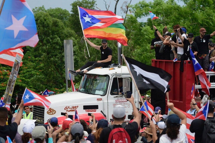 Ricky Martin, holding a Puerto Rican flag and a rainbow banner, joins thousands of Puerto Ricans for what many are expecting 