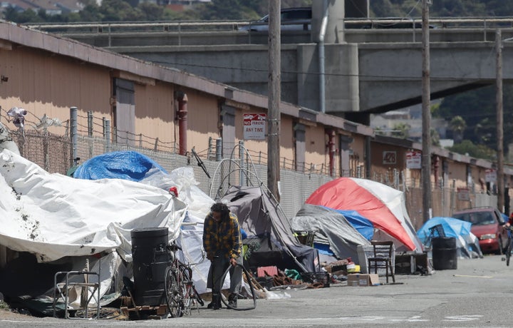 A man holding a bicycle tire outside of a tent along a street in San Francisco on June 27, 2019.