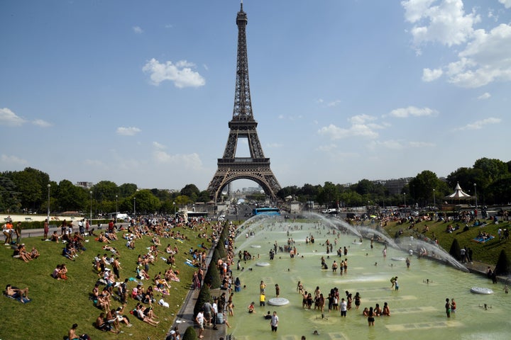 People cool off and sunbathe by the Trocadero Fountains next to the Eiffel Tower in Paris, on July 25, 2019 as a new heatwave hits the French capital. (BERTRAND GUAY/AFP/Getty Images)