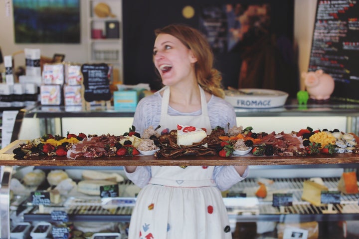 A staff member holds up a majestic meat and cheese board.