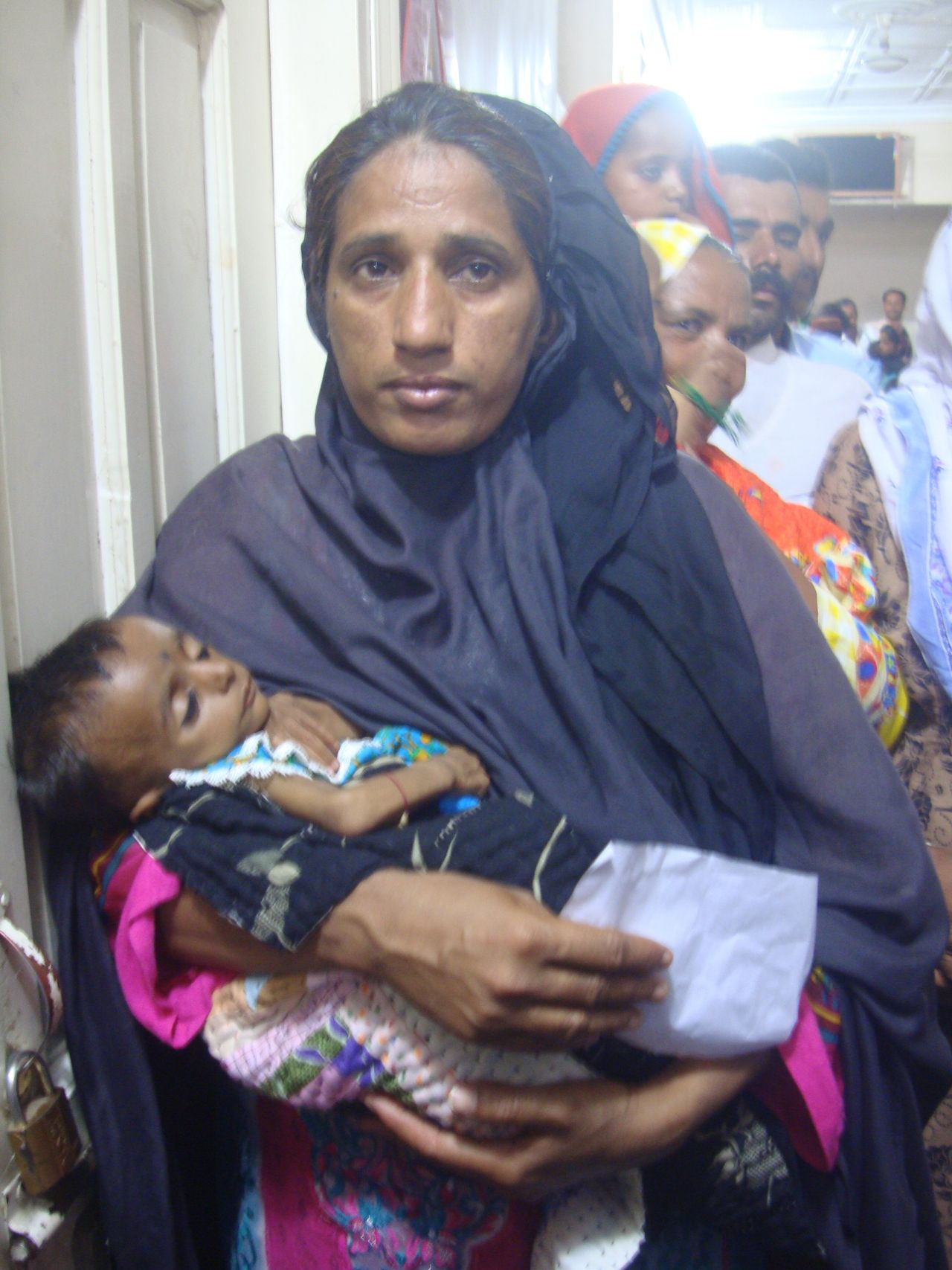 <em>A woman carries her malnourished baby while waiting for her turn to see HIV experts at the Chandka Medical Hospital, Larkana.</em>