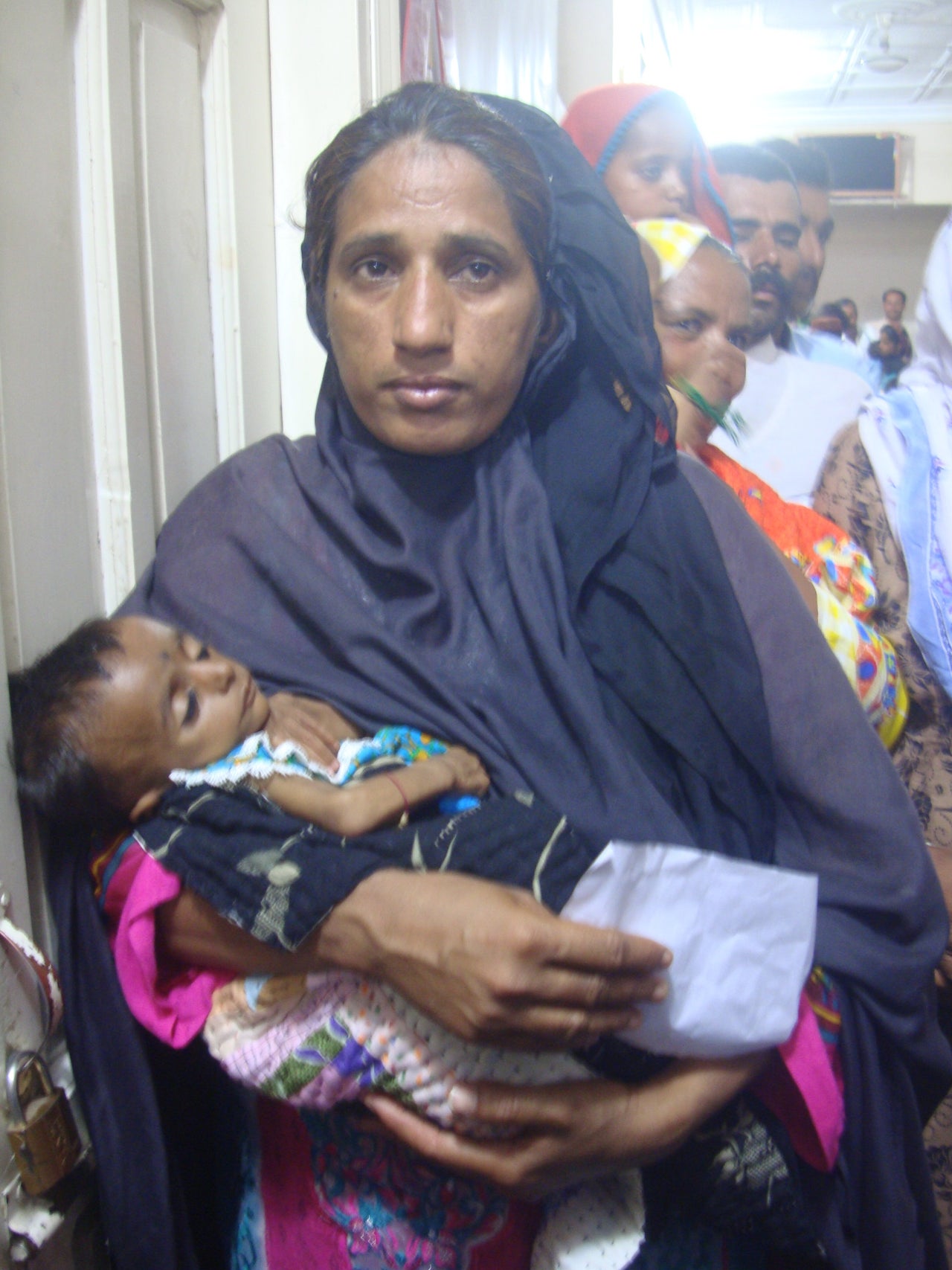 A woman carries her malnourished baby while waiting for her turn to see HIV experts at the Chandka Medical Hospital, Larkana.