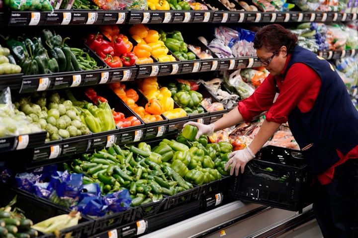 A Walmart worker stocks produce, some of it packaged in single-use plastic.