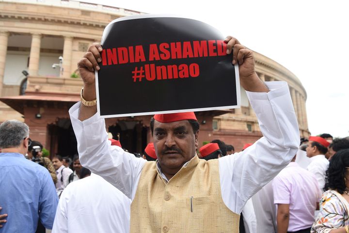 A member of the parliament of Samajwadi Party displays a placard during a protest calling for action in the Unnao rape case, at the Parliament House in New Delhi on July 30, 2019