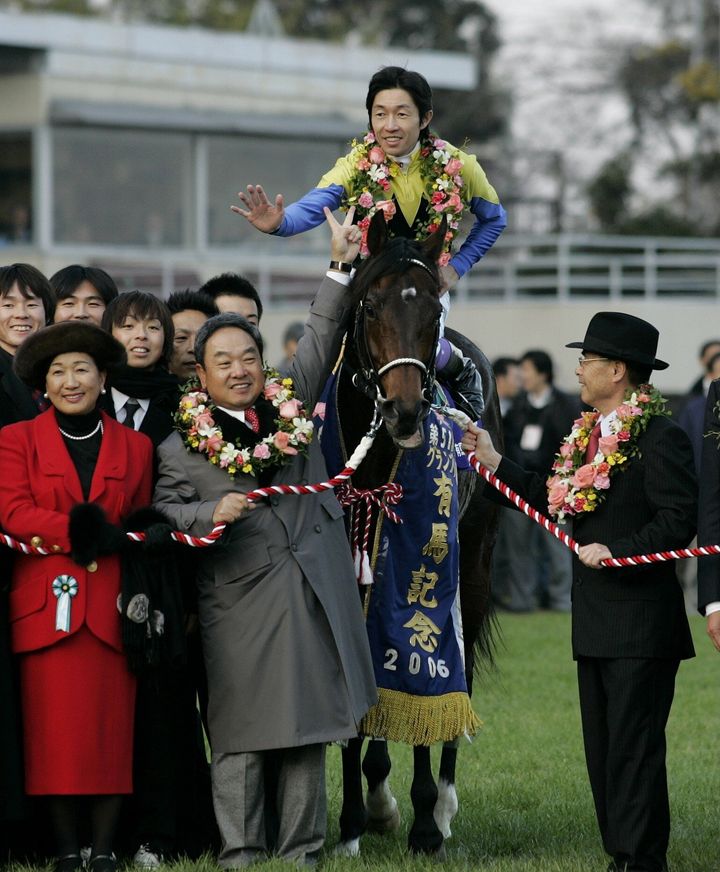 有馬記念を制した際のディープインパクトと武豊騎手（馬上）。Ｖサインする馬主の金子真人氏（千葉・中山競馬場、2006年12月24日）