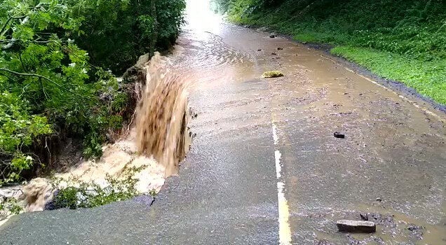 A damaged road and floodwater on the B6270 between Downhome and Grinton, North Yorkshire.