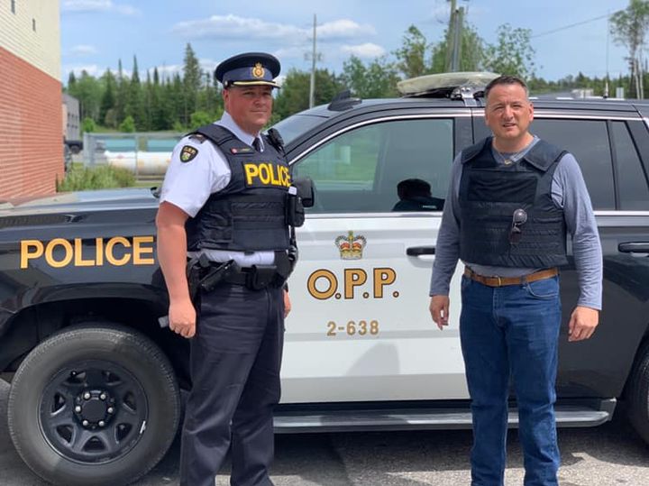 Ontario Minister of Indigenous Affairs Greg Rickford poses with a police officer in Kenora, Ont.