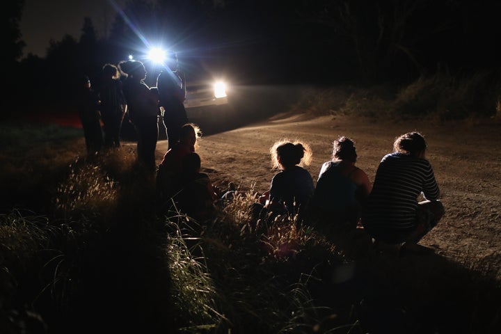 A U.S. Border Patrol vehicle illuminates a group of Central American asylum-seekers before taking them into custody near the U.S.-Mexico border on June 12, 2018, in McAllen, Texas. The group of women and children had rafted across the Rio Grande from Mexico and were detained by U.S. Border Patrol agents before being sent to a processing center for possible prosecution and separation.