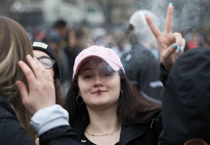 A woman flashes the peace sign as she smokes marijuana during the annual 420 rally on Parliament Hill in Ottawa April 20, 2019. 