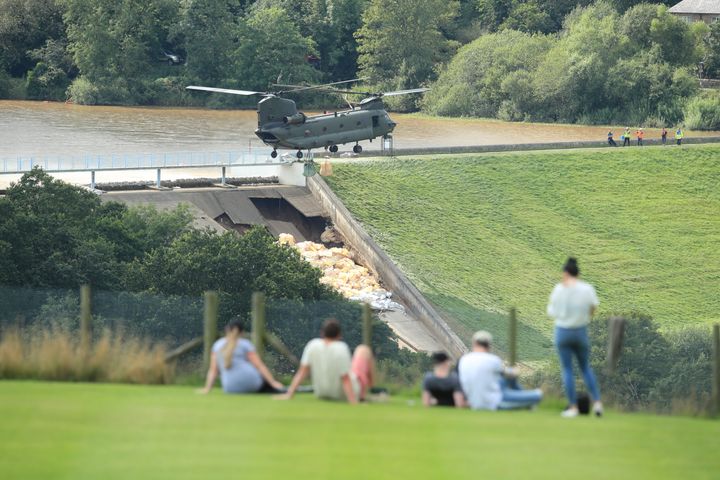 An RAF Chinook helicopter flies in sandbags to help repair the dam at Toddbrook reservoir near the village of Whaley Bridge in Derbyshire after it was damaged by heavy rainfall.