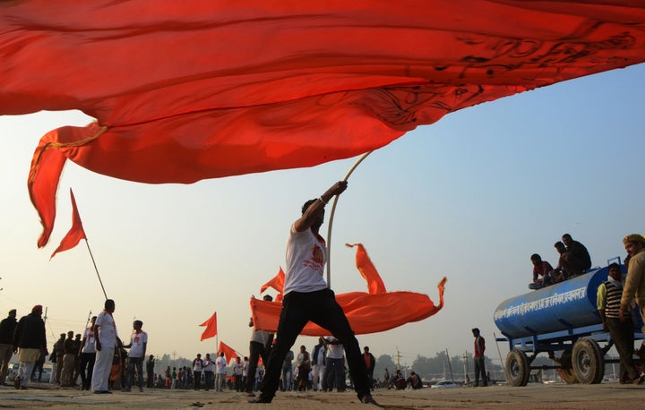 Hindu devotees host religious saffron flag during a royal religious procession of 'Niranji Akhara' called ' Peshwai' at the sangam, confluence of Ganga, Yamuna and the mythological Saraswati river, in Allahabad on 2 January, 2019 . 