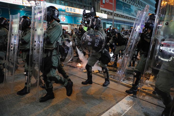 Riot police extinguish a fire set off by protesters in Hong Kong on Saturday.
