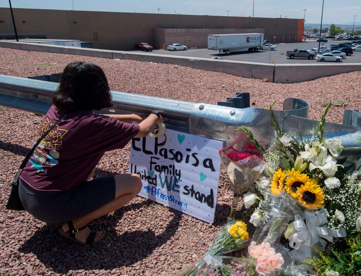 A woman places a Stay Strong sign beside a makeshift memorial in El Paso, Texas.