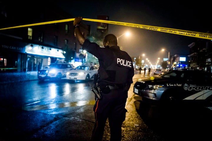 A police officer lifts police tape near the scene of a shooting in Toronto, on July 23, 2018.
