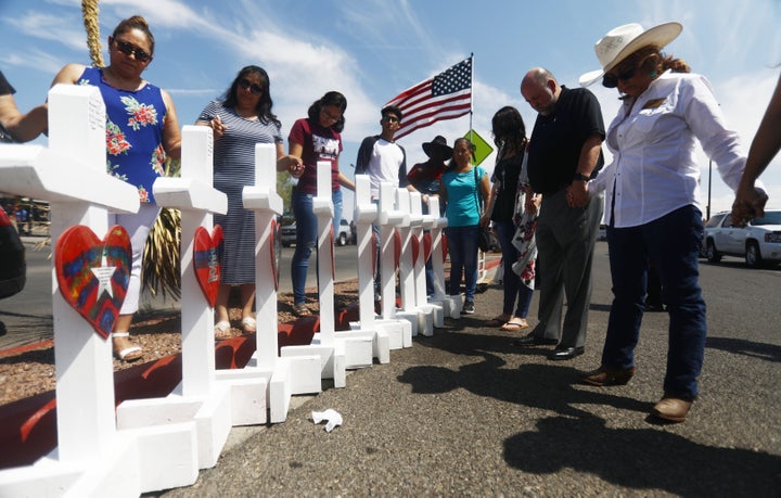 Volunteers pray over white handmade crosses memorializing the victims of a mass shooting which left at least 22 people dead on Aug. 5, 2019 in El Paso, Texas. The crosses were made by retired carpenter Greg Zanis.