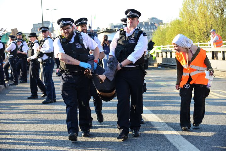 Police officers arrest a climate change protester on Waterloo Bridge in London in April, as a member of Extinction Rebellion's arrestee support speaks to the activist being carried off.