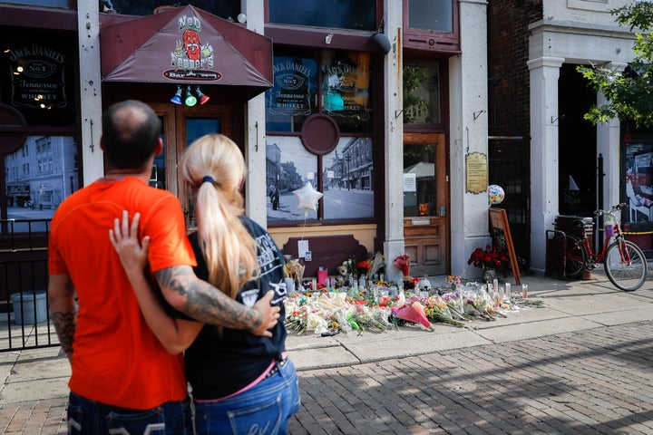 Mourners pause at a makeshift memorial for the slain and injured after a mass shooting that occurred early Sunday morning in Dayton, Ohio.